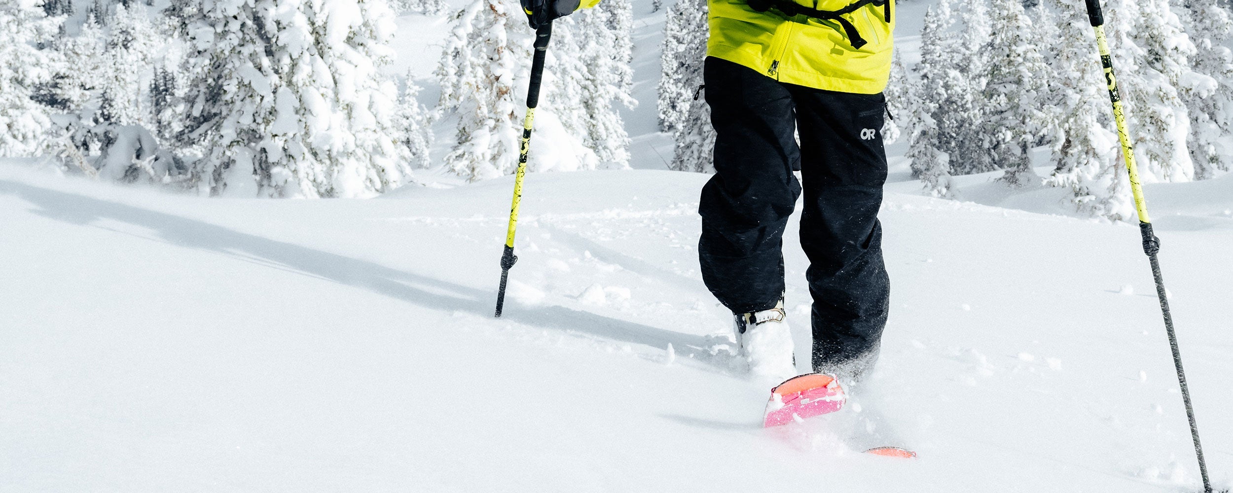 Man wearing Outdoor Research snow pants as he traverses up a snowy mountain. 