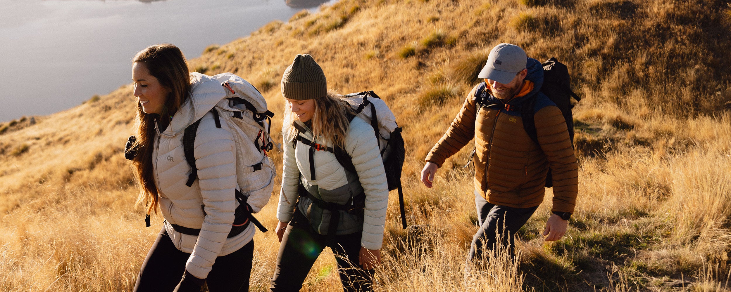 A group of friends climb to the viewpoint on a hike while wearing Outdoor Research Transcendent Down Hoodies. 