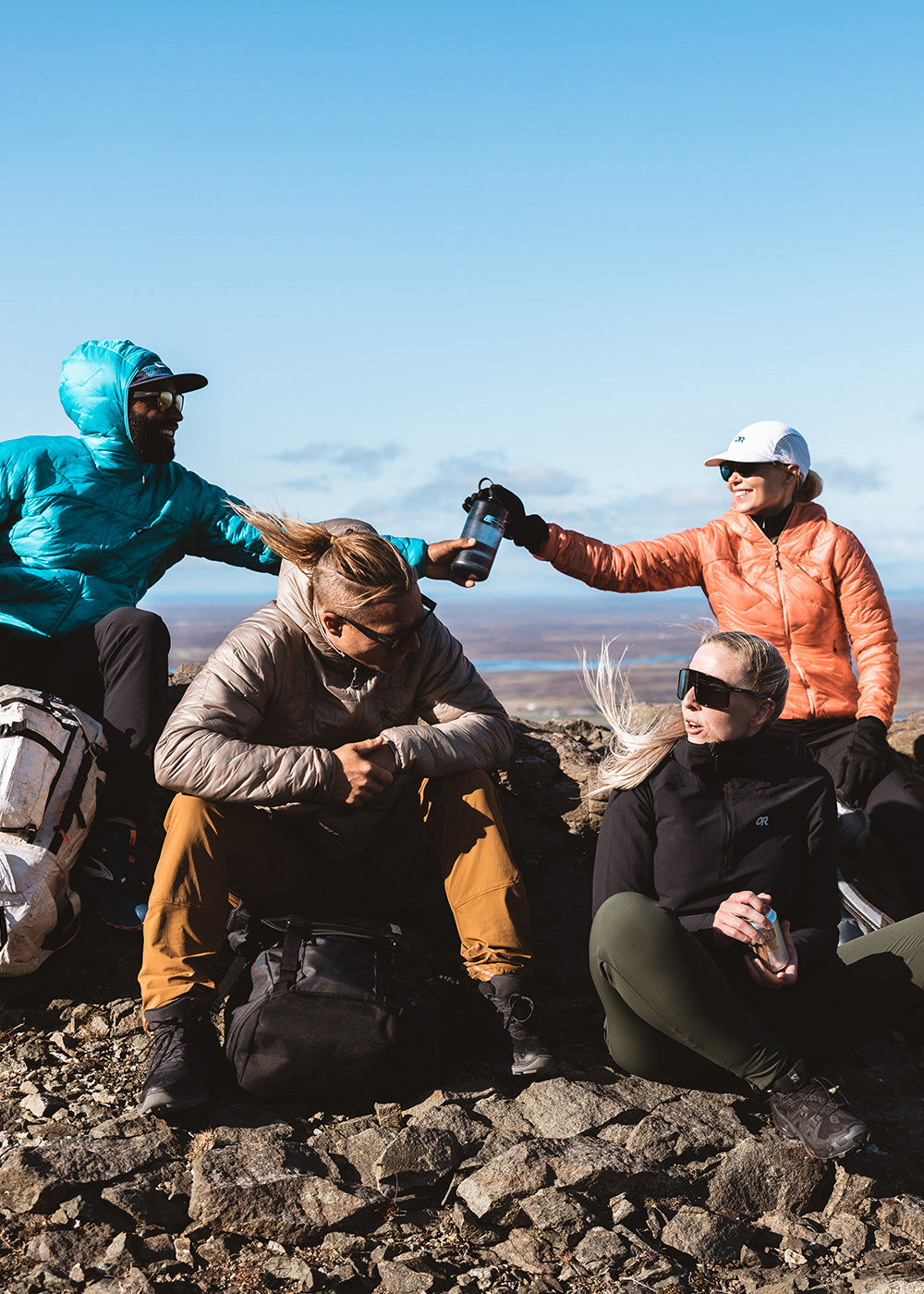 A group of friends wearing Outdoor Research Superstrand LT Hoodies take a break while out hiking.