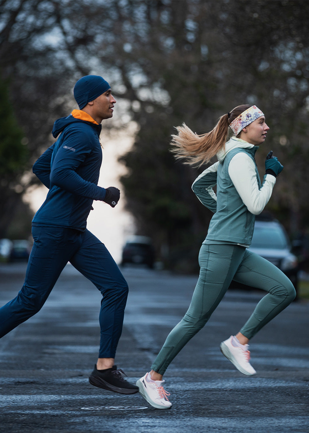 Two runners jog across the crosswalk wearing Outdoor Research Deviator styles.. 