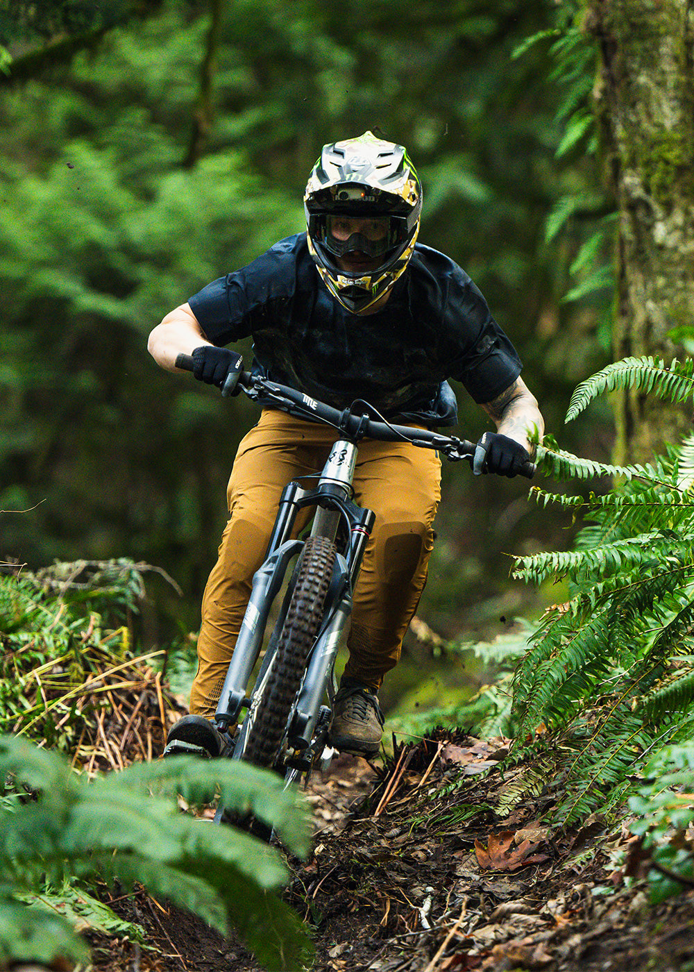 Man bikes downhill in forest while wearing the Outdoor Research Freewheel Mountain Bike Collection. 