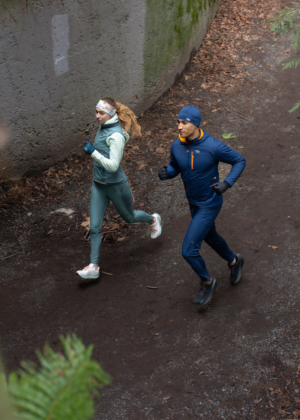 Two friends wear Outdoor Research running clothes while out for a run along a dirt trail.