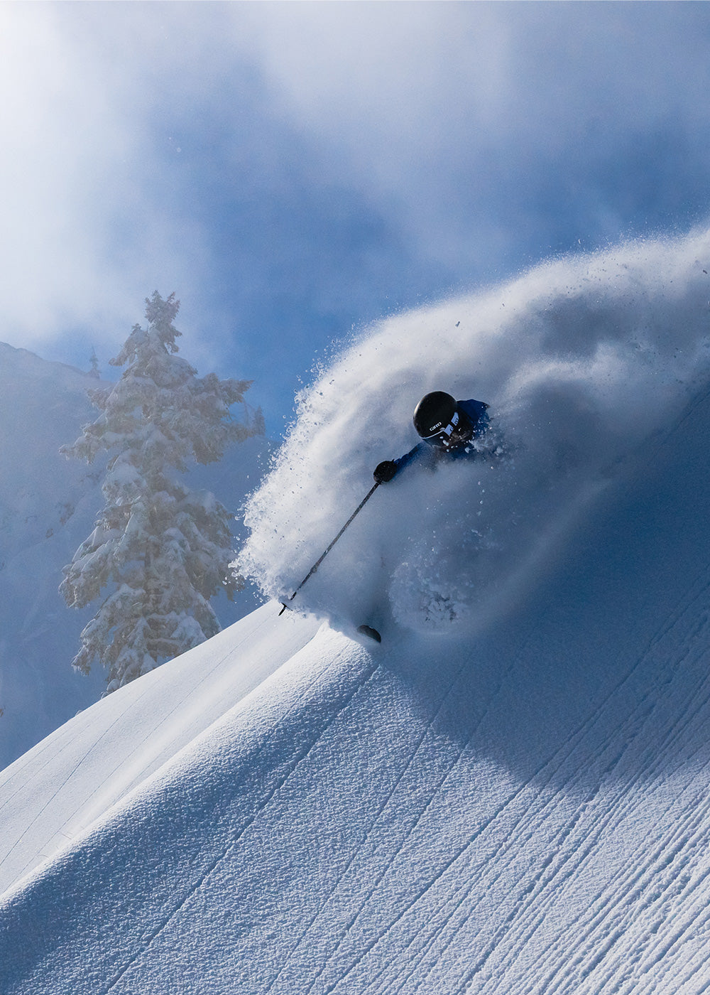 A skier skis through powder on a bluebird day.