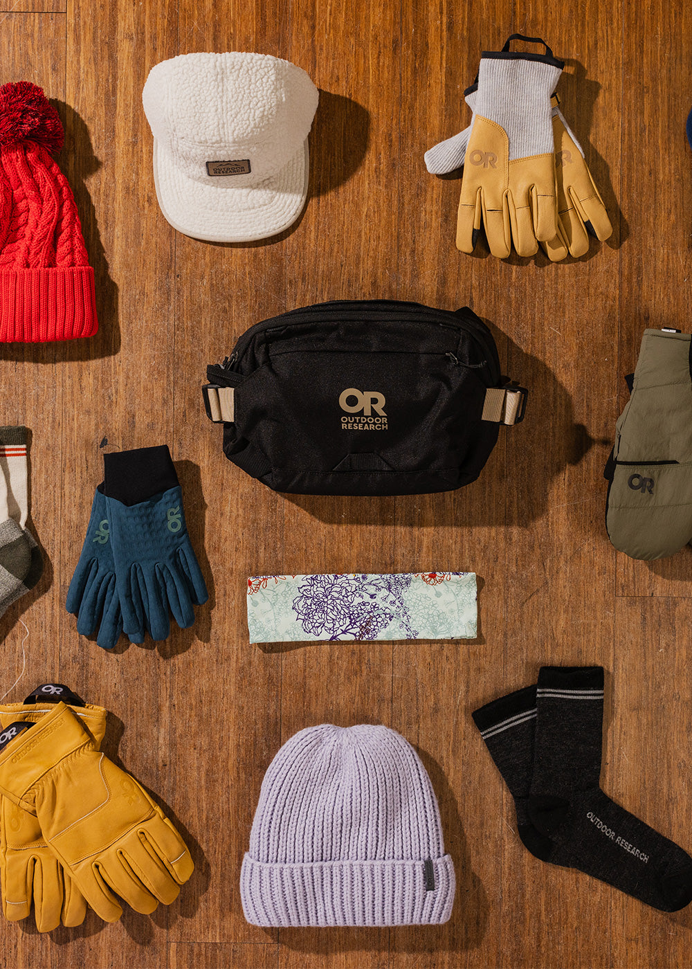 Overhead view of a variety of Outdoor Research hats, gloves, socks, and belt bags.