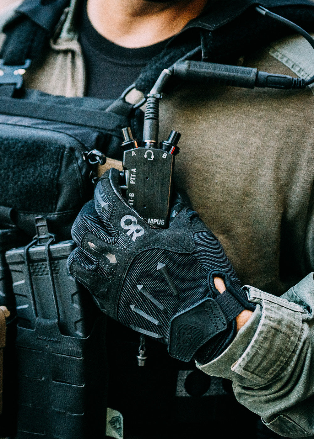 Close up of someone grabbing their radio while wearing a black OR Tactical glove.