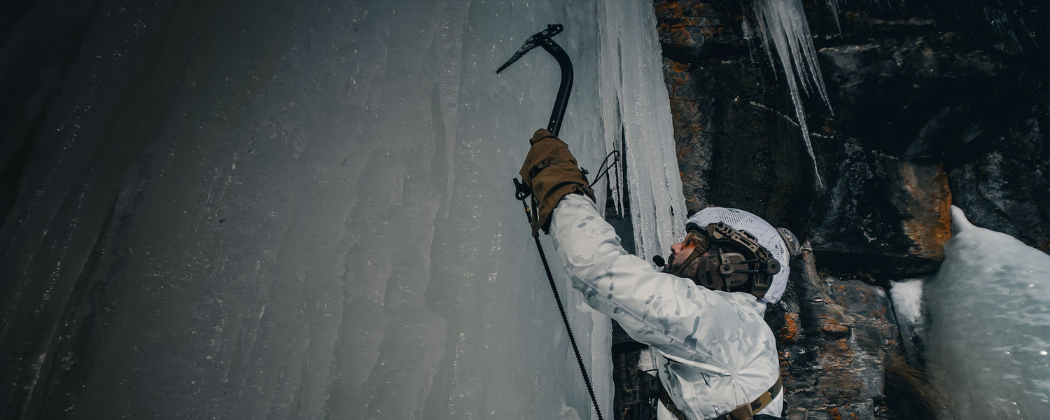 A man climbs an ice wall wearing Outdoor Research tactical outerwear.