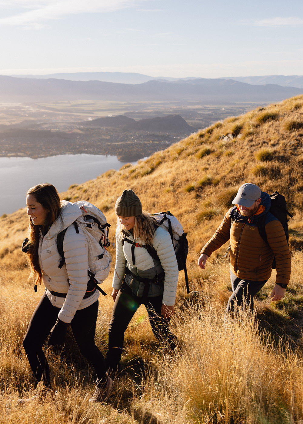 A group of friends climb to the viewpoint on a hike while wearing Outdoor Research Transcendent Down Hoodies. 