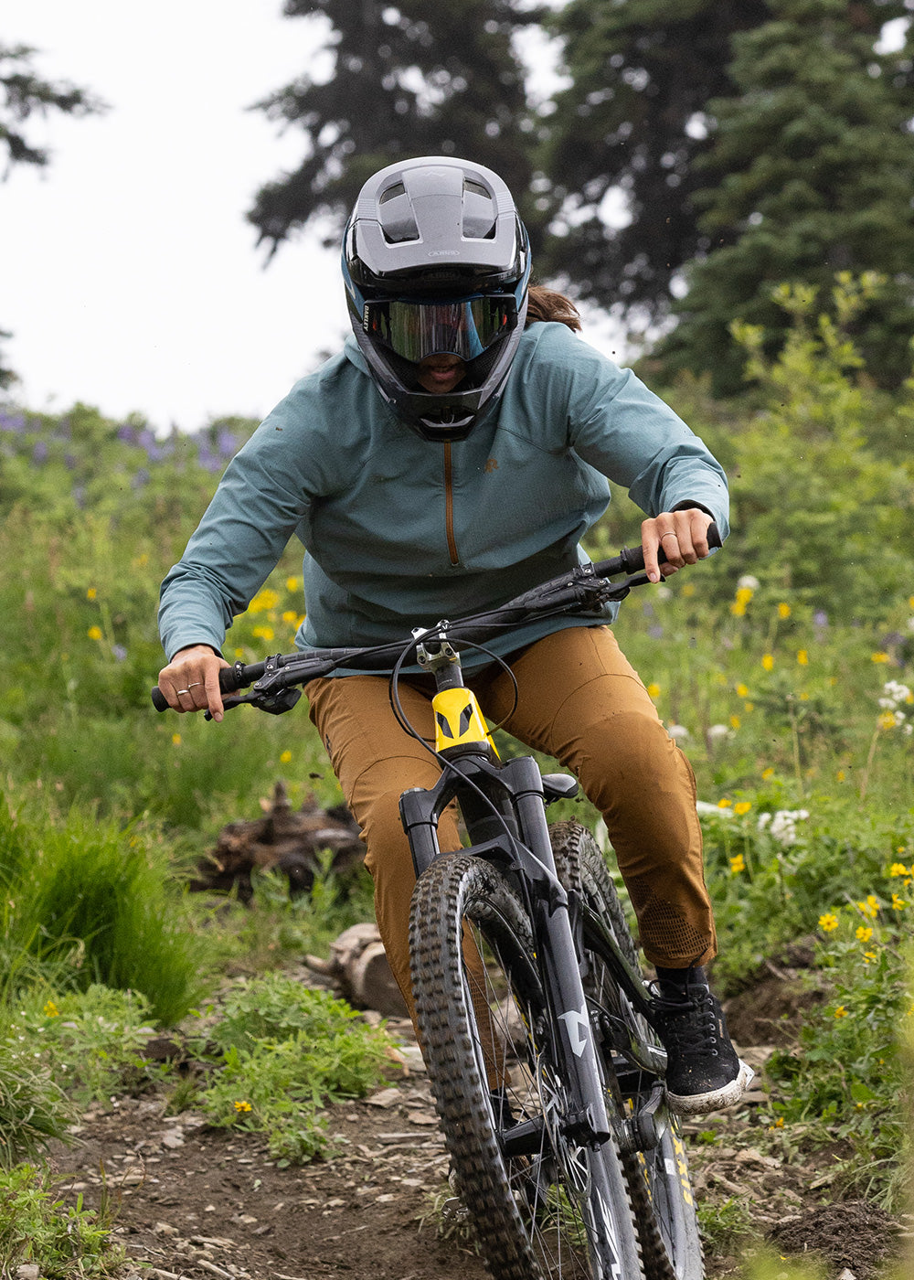 Outdoor Research mountain bike athlete Georgia Astle rides down a trail wearing the Freewheel Half Zip Soft Shell MTB Hoodie. 