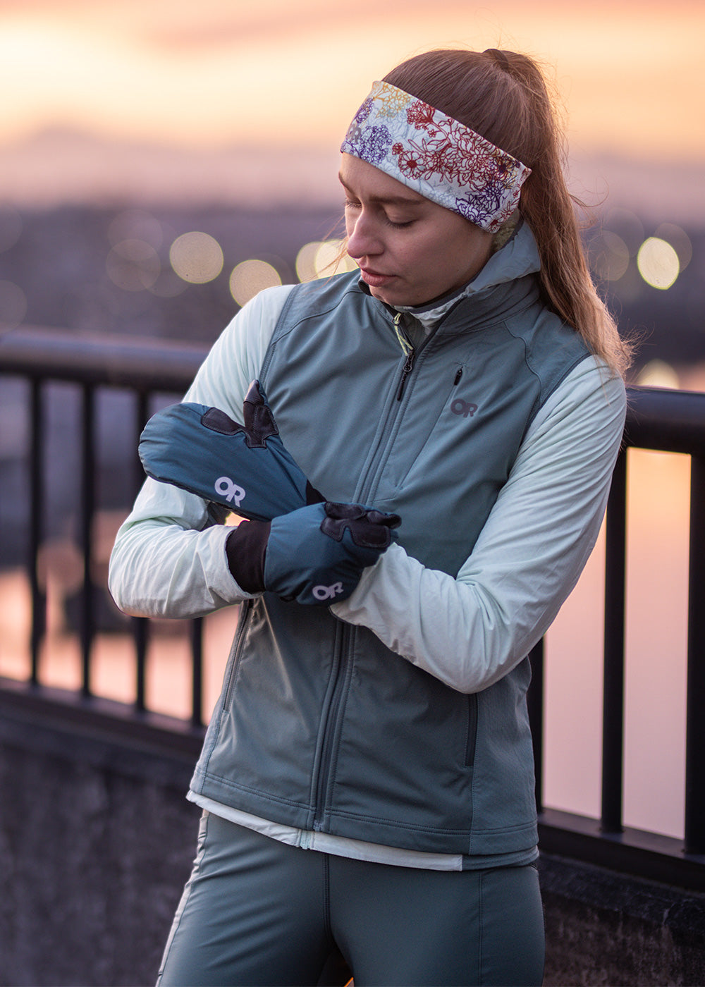 A woman wearing the Outdoor Research Deviator Sportswear collection tightens her Deviator Mitts in Harbor blue before a run. 