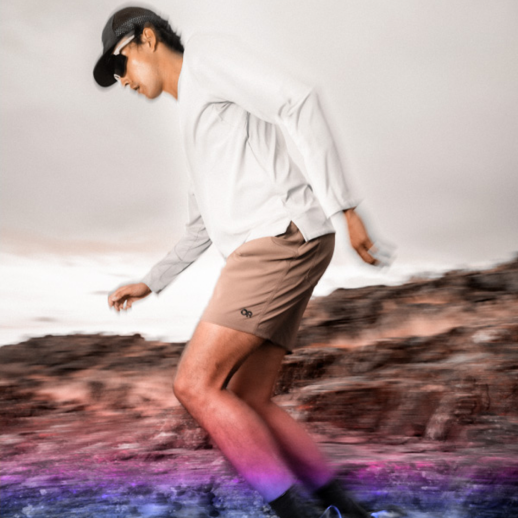 Man wearing Outdoor Research ActiveIce Sprectrum Sun Hoodie Runs across rocks. 