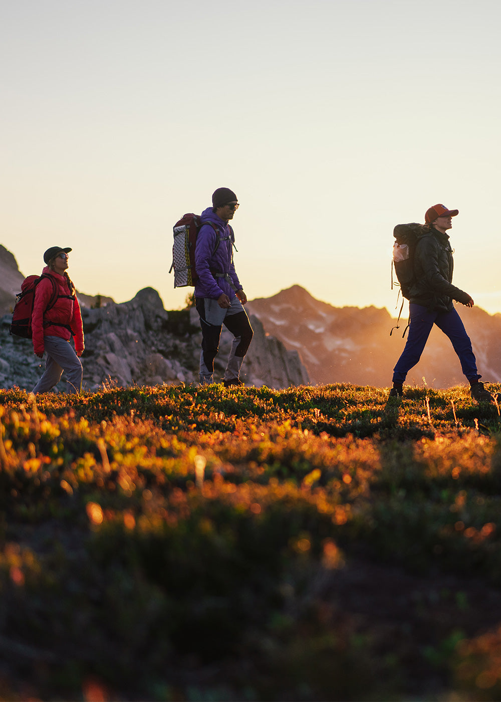 Four friends hike along a mountain ridge at sunset.