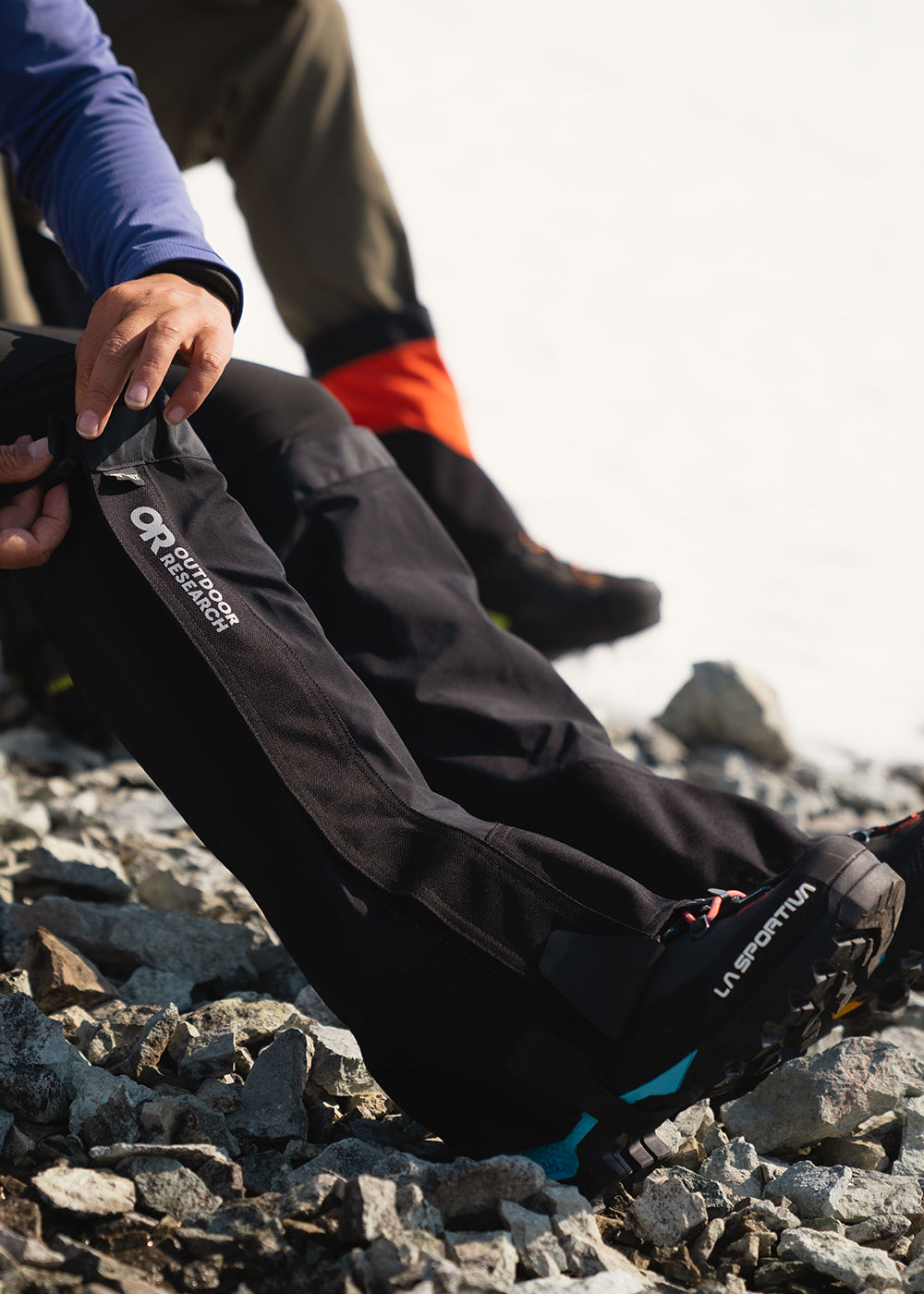 Woman straps on a pair of Outdoor Research Crocodile Gaiters in Black. 