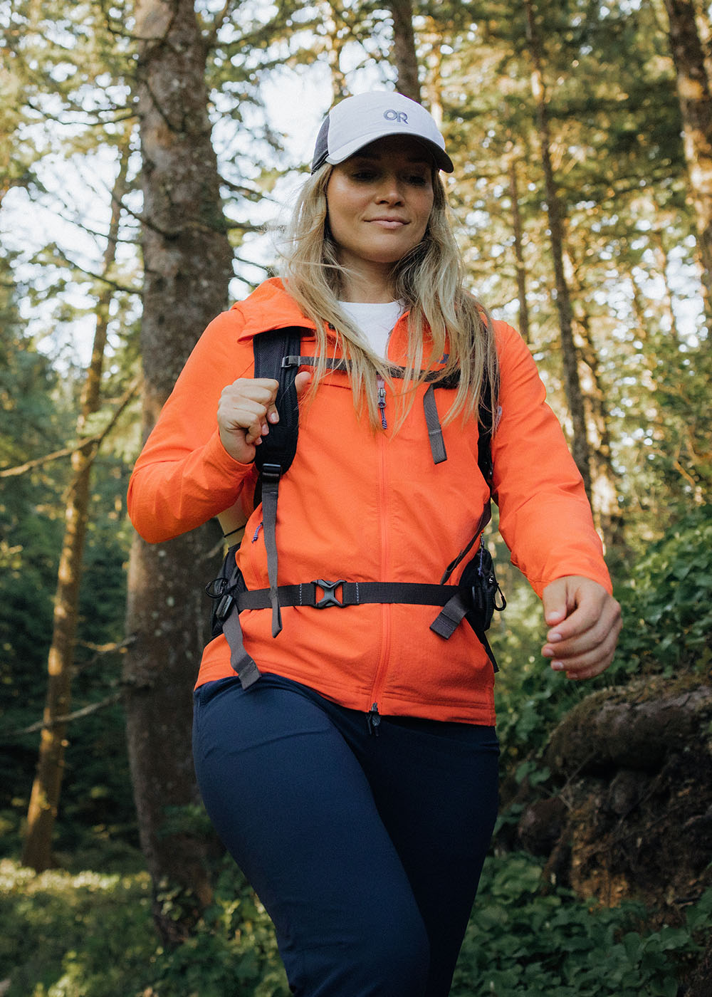 Woman hikes through the woods in the sun.