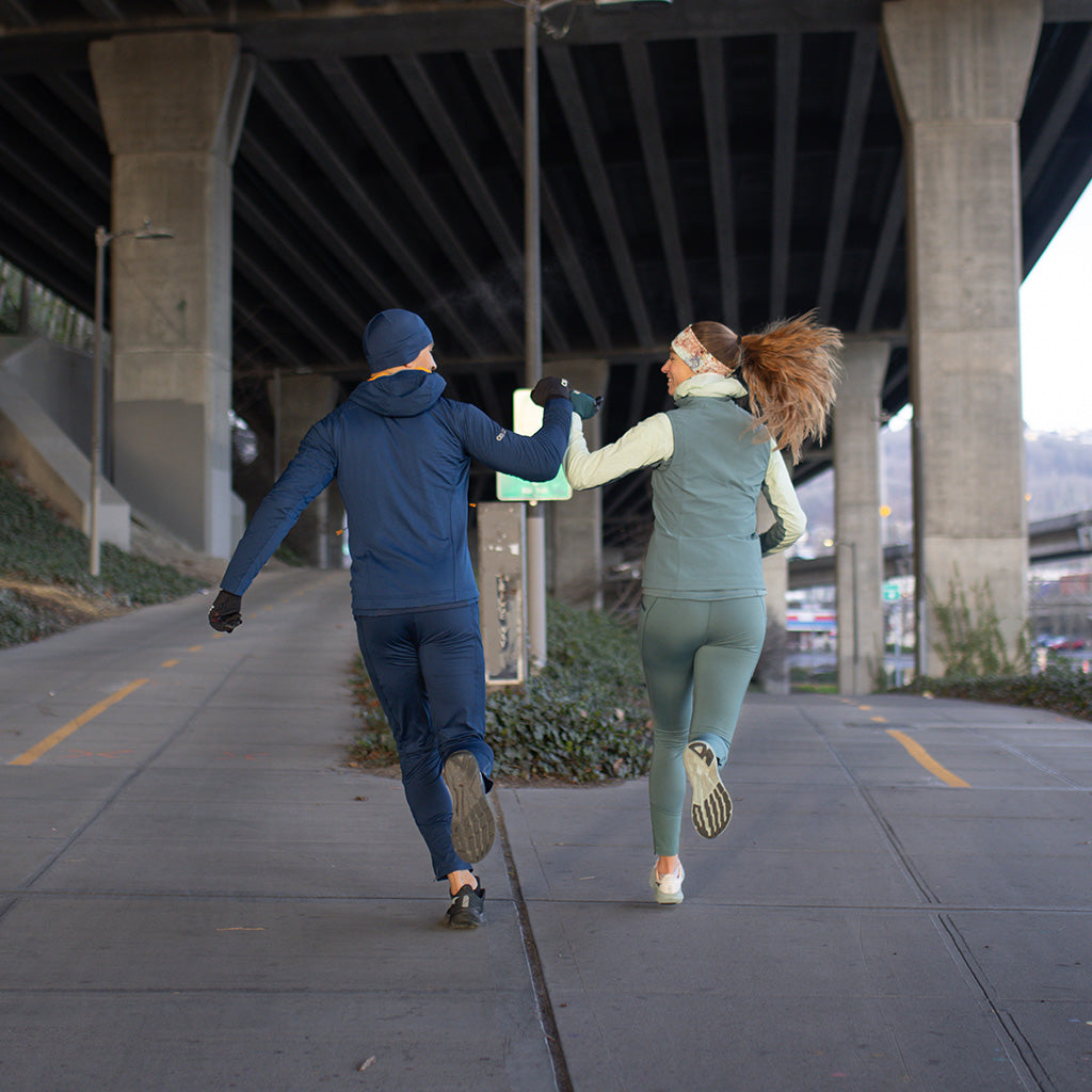 Two friends high five during their run while wearing the Outdoor Research Deviator Sportswear Collection. 