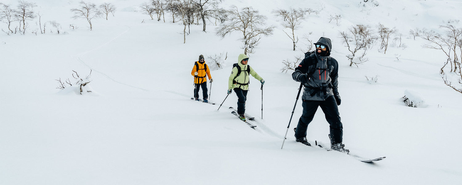 3 friends wearing Outdoor Research ski Outerwear traverse through the snow while looking at the views around them. 