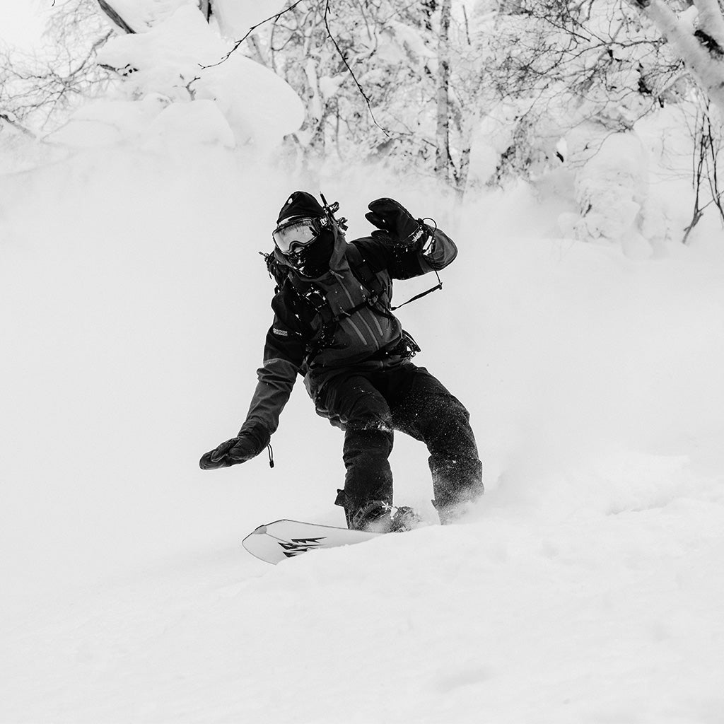 A snowboarder wearing Outdoor Research outwear rides through powder.