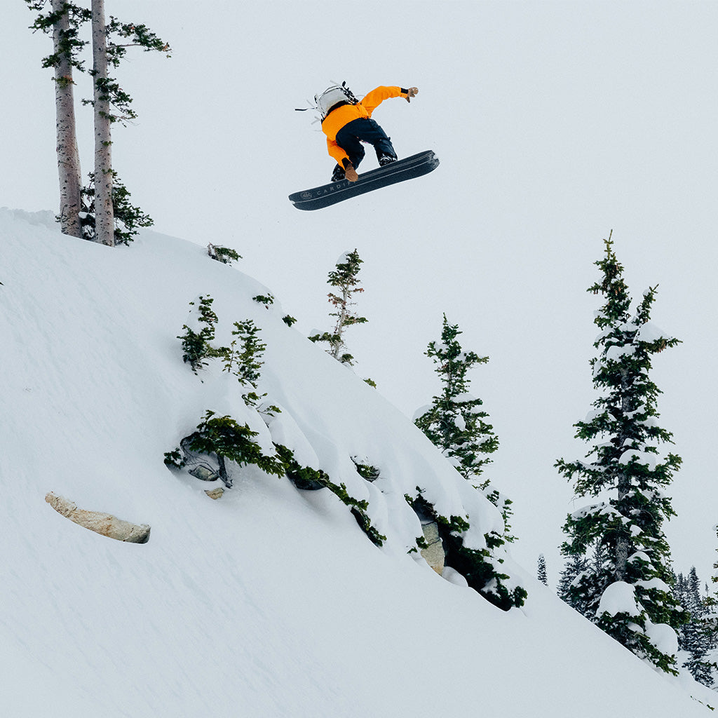 A snowboarder jumps off a snowy cliff.