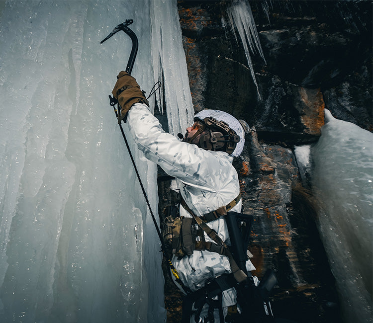 A man climbs an ice wall wearing Outdoor Research tactical outerwear.